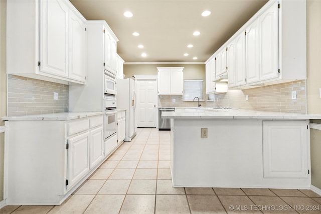 kitchen with white appliances, light tile patterned flooring, backsplash, kitchen peninsula, and white cabinets