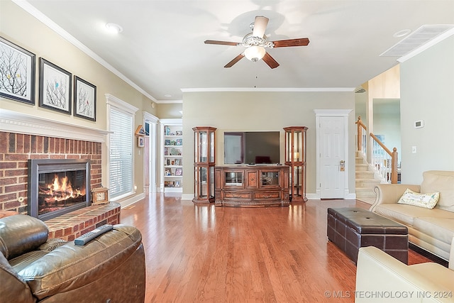 living room featuring ornamental molding, hardwood / wood-style flooring, a fireplace, and ceiling fan