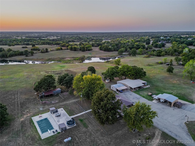 aerial view at dusk featuring a water view