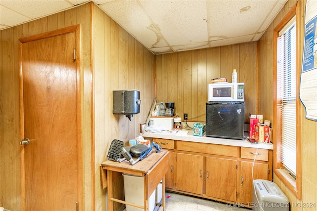 kitchen with wood walls and a drop ceiling