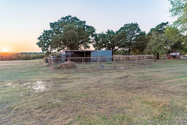 yard at dusk featuring a rural view and an outdoor structure