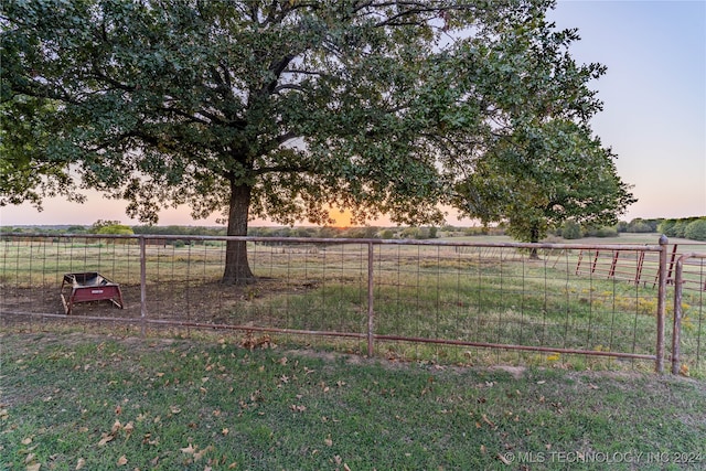 yard at dusk featuring a rural view