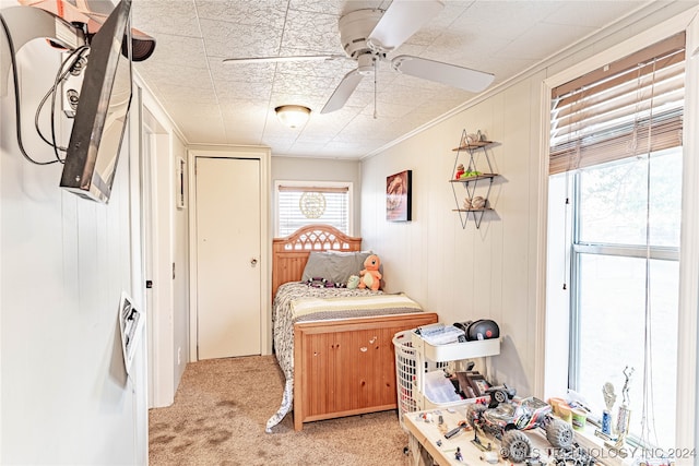 carpeted bedroom featuring crown molding, wooden walls, and ceiling fan