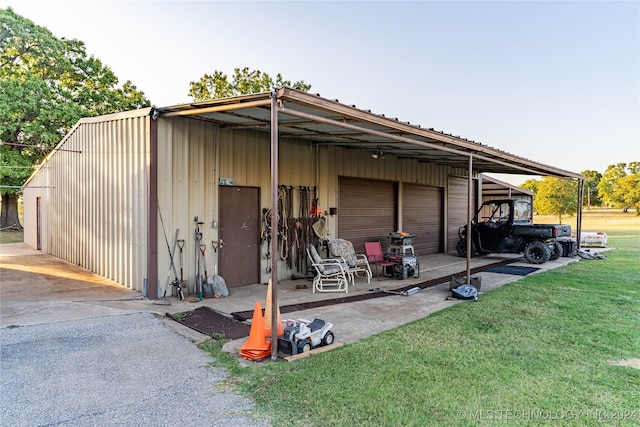 view of outdoor structure featuring a carport, a lawn, and a garage