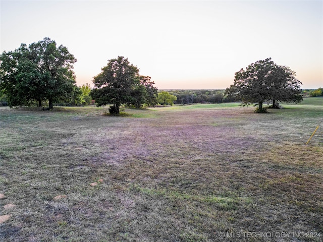 yard at dusk featuring a rural view