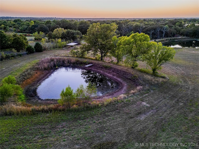 aerial view at dusk featuring a water view