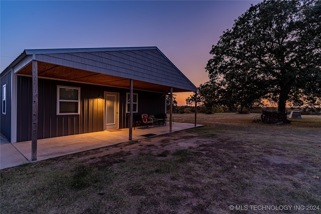 back house at dusk with a yard and a patio area