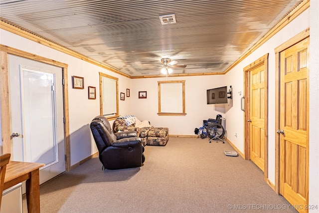 living area with ornamental molding, light colored carpet, and ceiling fan