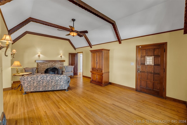 living room with a stone fireplace, vaulted ceiling with beams, light hardwood / wood-style floors, and ceiling fan