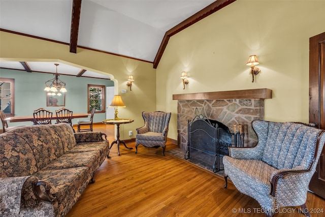 living room featuring lofted ceiling with beams, a stone fireplace, and hardwood / wood-style flooring