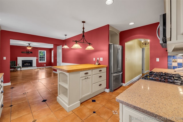 kitchen featuring butcher block counters, white cabinets, decorative light fixtures, appliances with stainless steel finishes, and ceiling fan