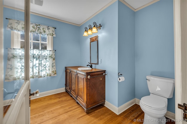 bathroom featuring vanity, ornamental molding, wood-type flooring, and toilet