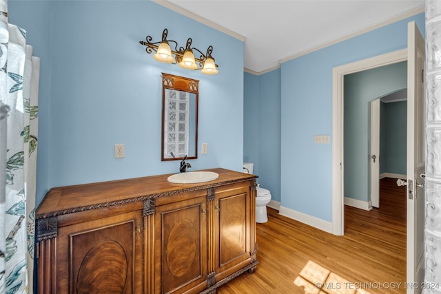 bathroom featuring vanity, crown molding, wood-type flooring, and toilet