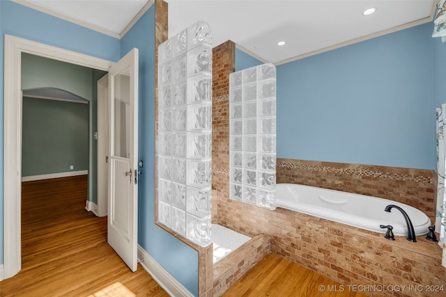 bathroom with tiled bath, ornamental molding, and hardwood / wood-style floors