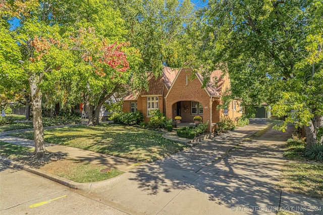 english style home featuring a front yard and a garage