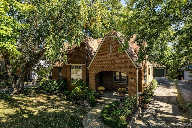 tudor home with a garage and a front lawn