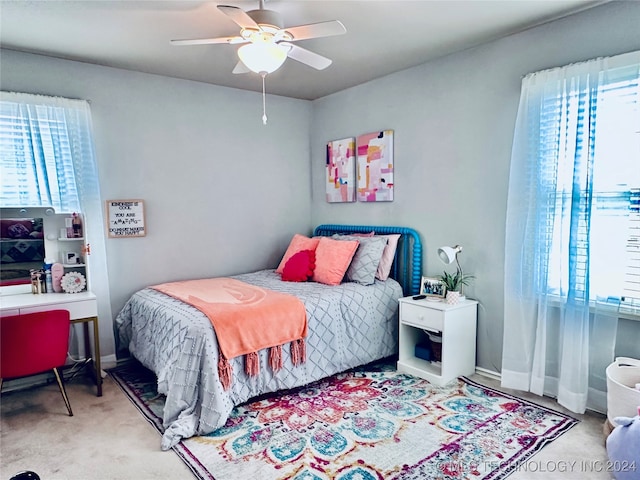 carpeted bedroom featuring multiple windows and ceiling fan