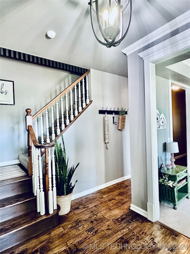 stairway featuring ornamental molding, hardwood / wood-style floors, and an inviting chandelier