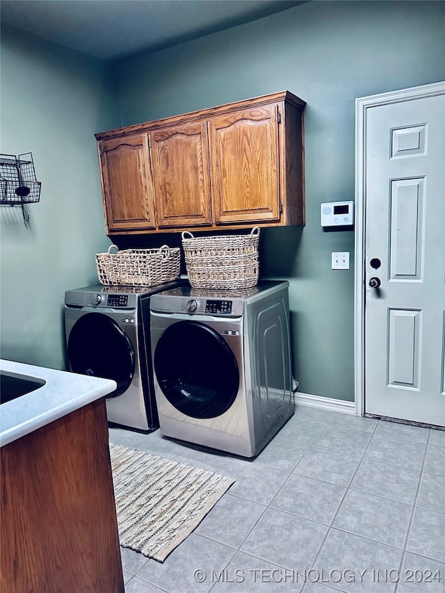 washroom featuring washer and dryer, cabinets, and light tile patterned floors