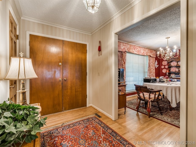 entrance foyer featuring ornamental molding, hardwood / wood-style floors, a notable chandelier, and a textured ceiling