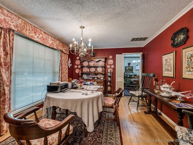 dining room featuring crown molding, hardwood / wood-style flooring, a textured ceiling, and an inviting chandelier