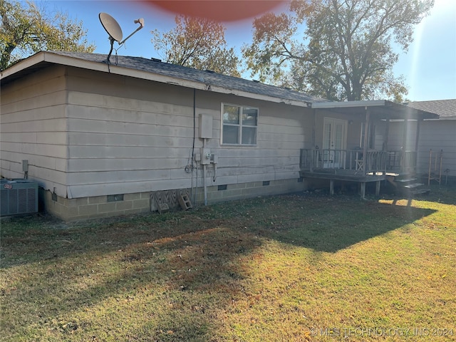 rear view of house featuring central AC unit and a lawn