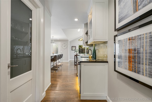 kitchen featuring decorative backsplash, white cabinetry, decorative light fixtures, and dark wood-type flooring