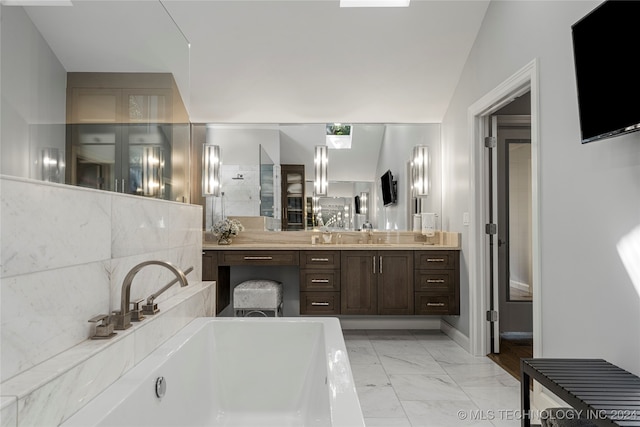 bathroom with vanity, vaulted ceiling, and a bath