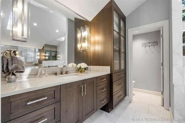 bathroom featuring vanity, toilet, and vaulted ceiling