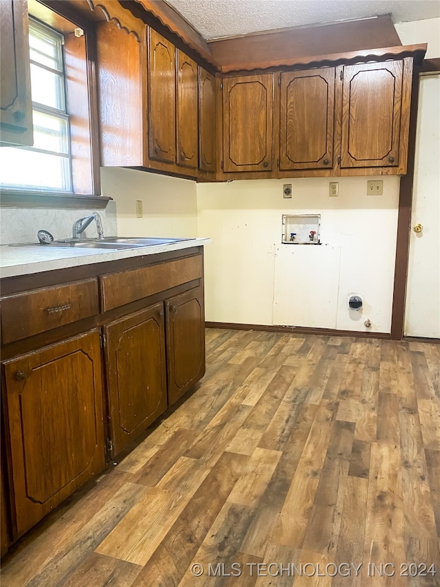 laundry room with hookup for a washing machine, sink, cabinets, a textured ceiling, and light hardwood / wood-style floors