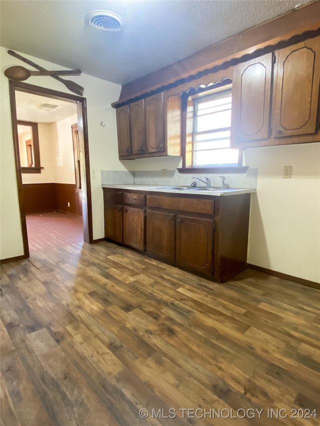 kitchen with dark brown cabinets, sink, dark wood-type flooring, and a textured ceiling