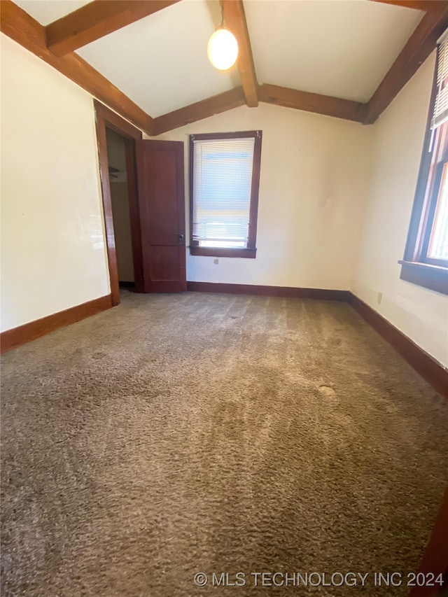 empty room with lofted ceiling with beams, carpet flooring, and a wealth of natural light