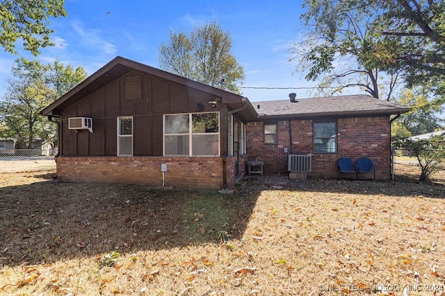 view of front of property with fence, brick siding, cooling unit, a wall unit AC, and board and batten siding