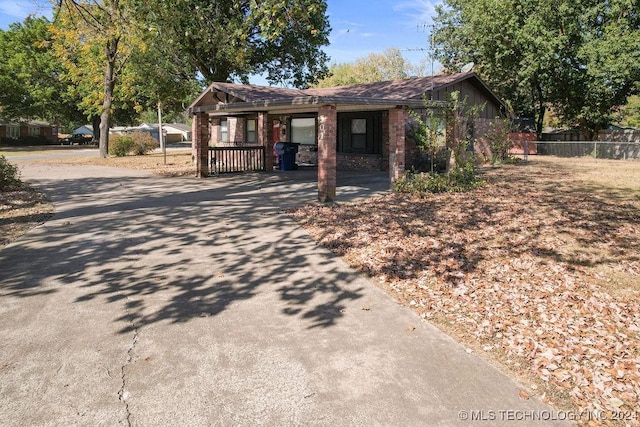 bungalow-style home with fence, a carport, and driveway