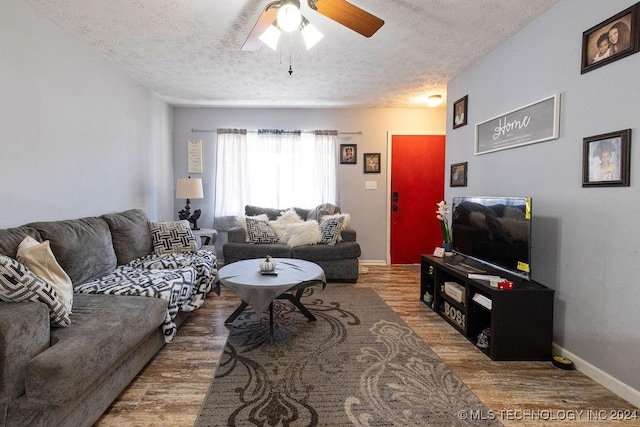 living area featuring a textured ceiling, wood finished floors, baseboards, and ceiling fan