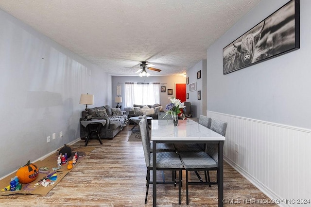 dining area featuring a textured ceiling, a ceiling fan, and wood finished floors