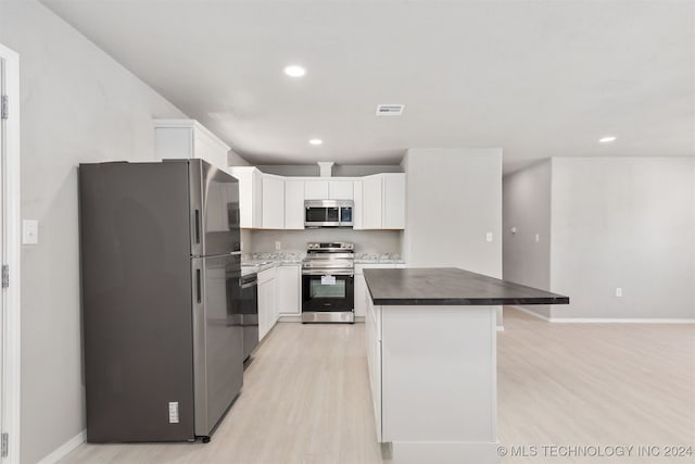 kitchen with stainless steel appliances, light wood-type flooring, a kitchen island, and white cabinets