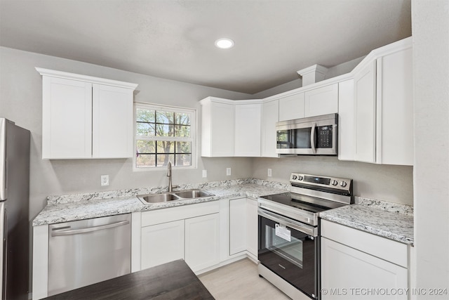 kitchen featuring light stone counters, stainless steel appliances, sink, and white cabinets