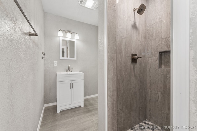 bathroom featuring vanity, hardwood / wood-style floors, and a tile shower