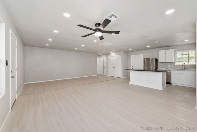 unfurnished living room featuring ceiling fan, sink, and light wood-type flooring