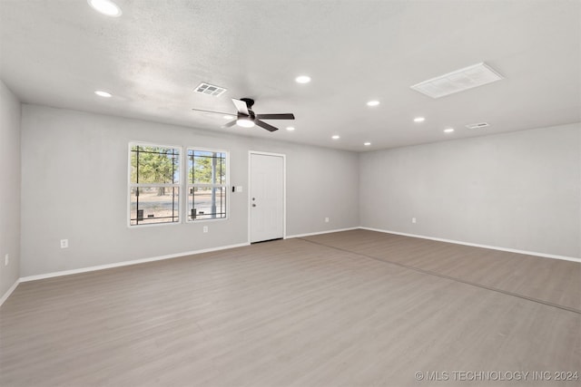 empty room with a textured ceiling, wood-type flooring, and ceiling fan