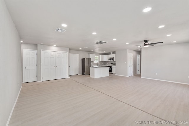 unfurnished living room with ceiling fan, sink, and light hardwood / wood-style flooring