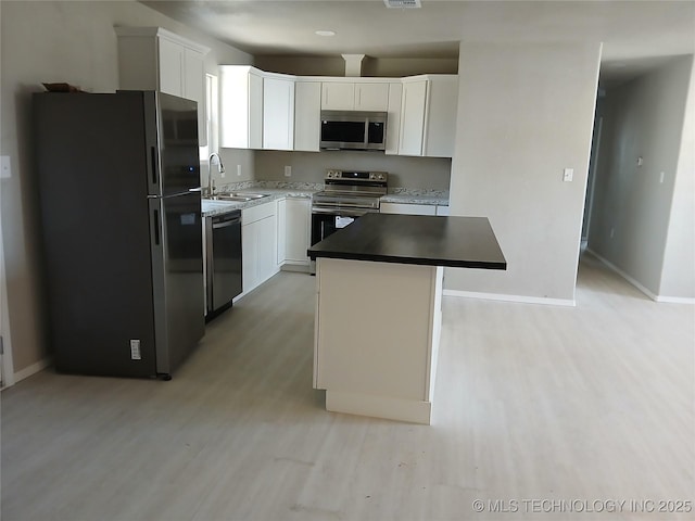 kitchen featuring a kitchen island, white cabinetry, sink, stainless steel appliances, and light hardwood / wood-style flooring