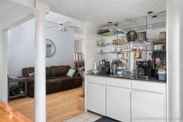 bar featuring decorative columns, light wood-type flooring, white cabinetry, a textured ceiling, and ceiling fan