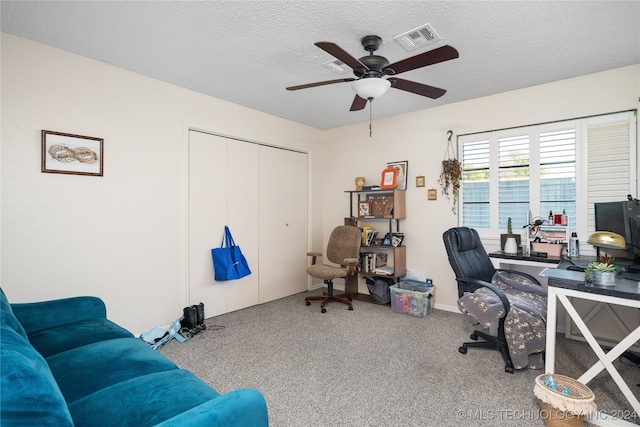 carpeted home office featuring a textured ceiling and ceiling fan