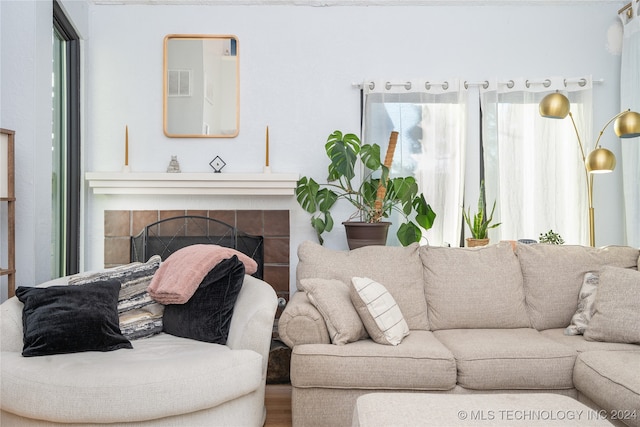 living room featuring a tiled fireplace, wood-type flooring, and a wealth of natural light