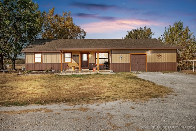 ranch-style home featuring covered porch and a yard