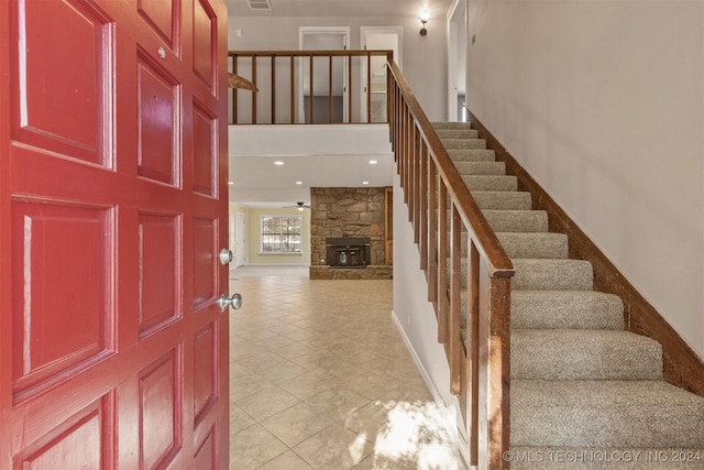 tiled foyer entrance with ceiling fan and a fireplace