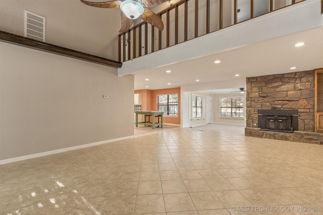 unfurnished living room featuring ceiling fan, a high ceiling, and light tile patterned floors