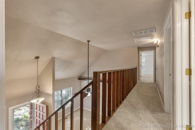 hallway with carpet floors and vaulted ceiling